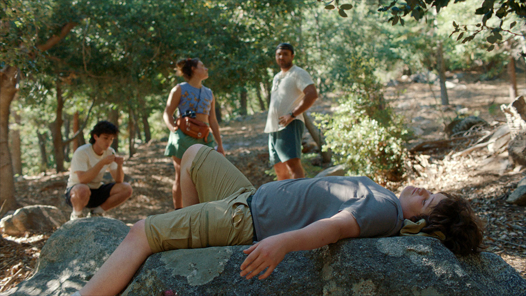 An image capturing a poignant moment from 'Big Boys', featuring the young protagonist Jamie in a reflective moment during a camping trip.